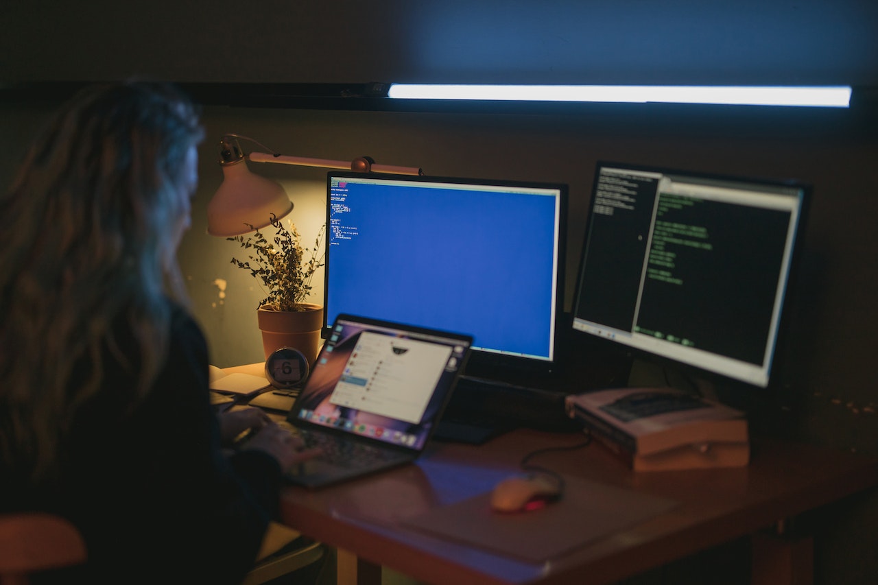 woman sitting in front of multiple computers dealing with mutli factor authentication